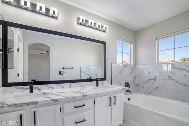 full bathroom with double vanity, a tub to relax in, and a sink