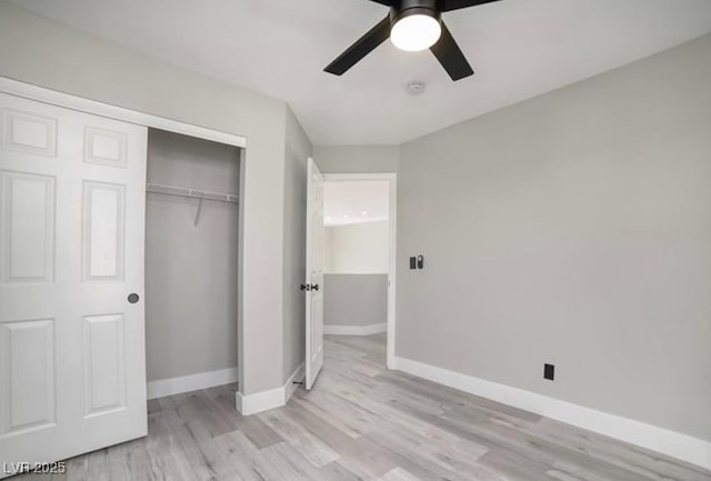 unfurnished bedroom featuring ceiling fan, a closet, baseboards, and light wood-style flooring