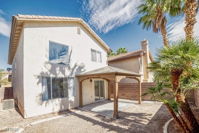 rear view of property with a gazebo, a patio, fence, and stucco siding