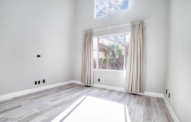 spare room featuring baseboards and light wood finished floors