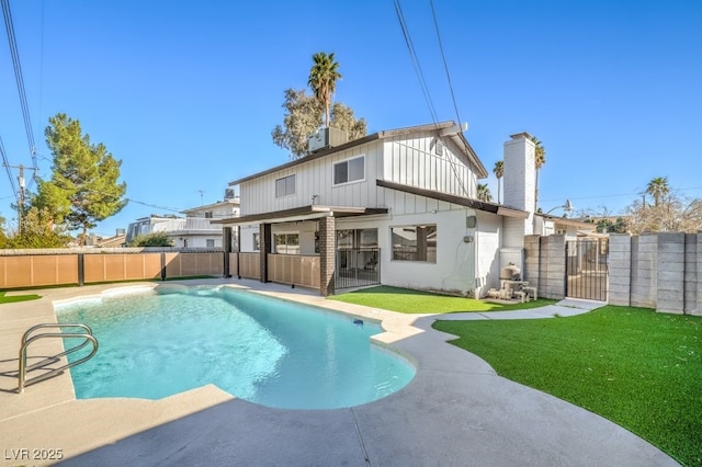 back of house with a fenced in pool, board and batten siding, a yard, a fenced backyard, and a gate