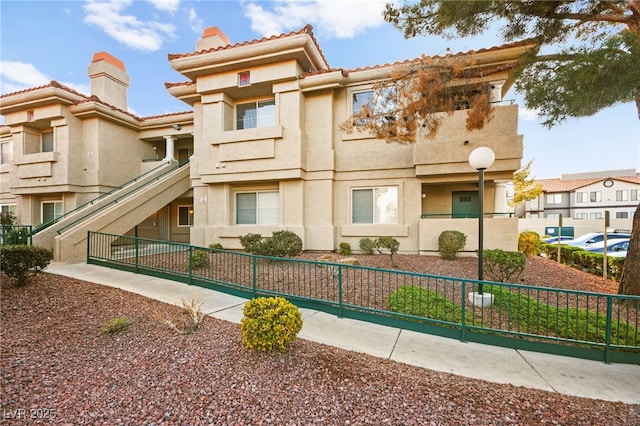 view of front of house featuring stucco siding, a chimney, and fence