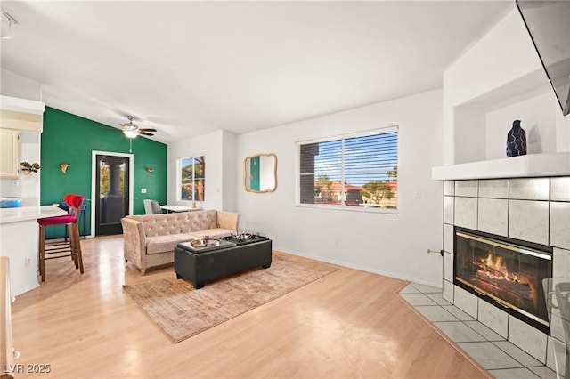 living area featuring ceiling fan, light wood-style flooring, and a fireplace