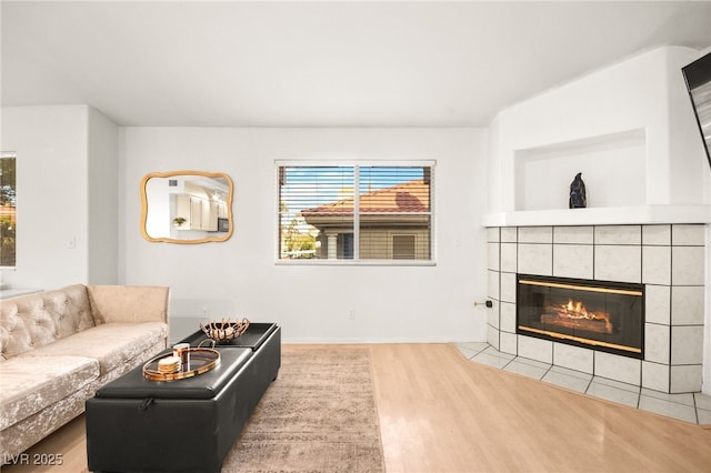 living room featuring a tiled fireplace, wood finished floors, and baseboards