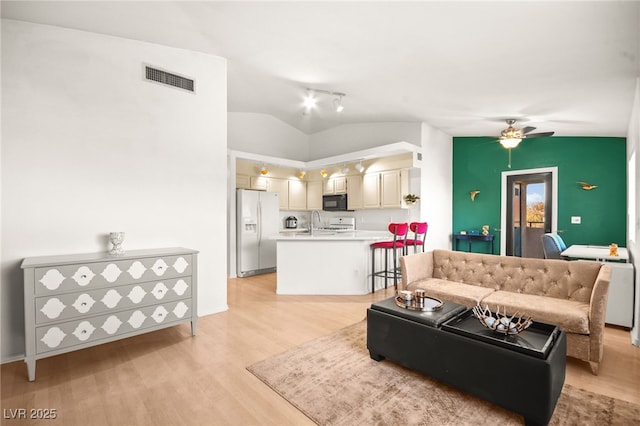 living room featuring visible vents, light wood-type flooring, ceiling fan, and vaulted ceiling