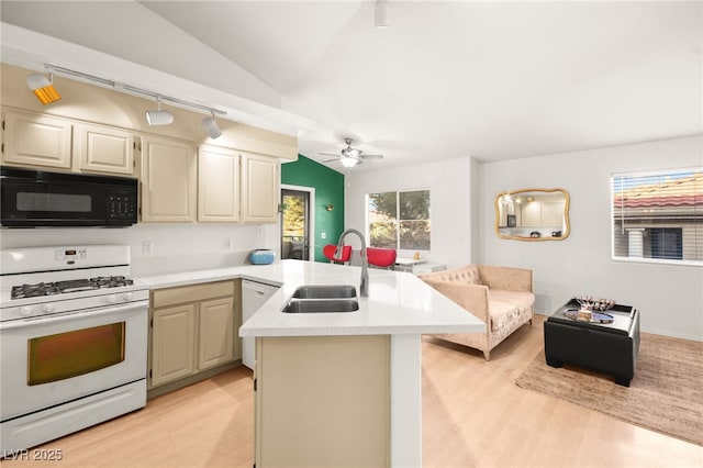 kitchen featuring white range with gas cooktop, a sink, a peninsula, black microwave, and lofted ceiling