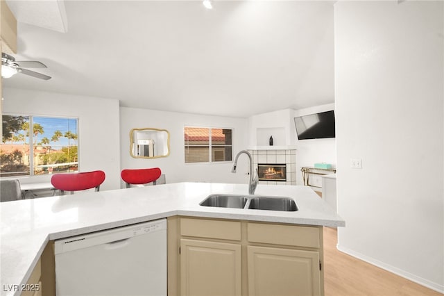 kitchen featuring open floor plan, light countertops, a tile fireplace, white dishwasher, and a sink