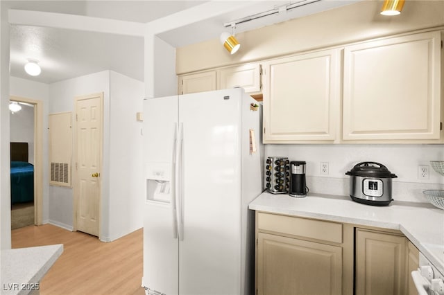 kitchen with visible vents, light wood finished floors, light countertops, white fridge with ice dispenser, and range