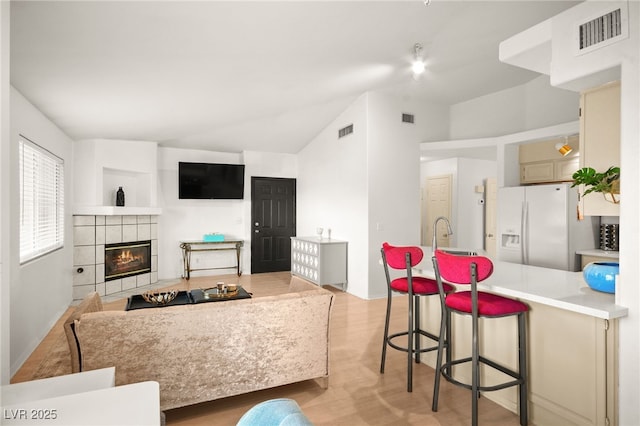 kitchen featuring a fireplace, visible vents, and white fridge with ice dispenser