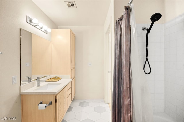 full bathroom featuring visible vents, vanity, and a tile shower