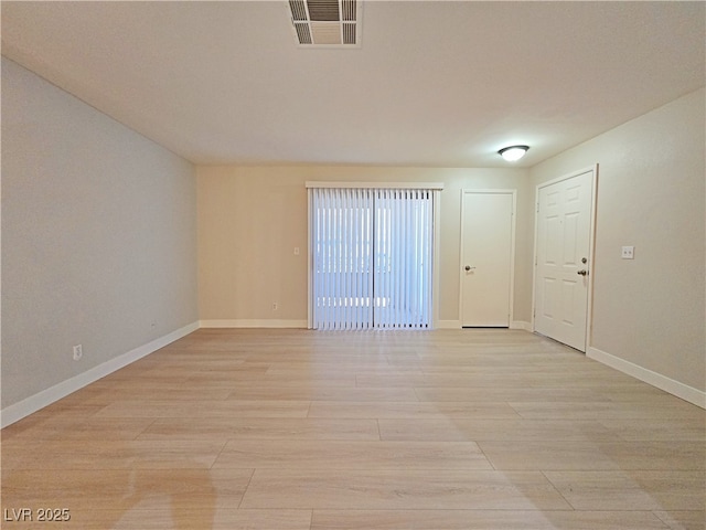 unfurnished room with light wood finished floors, visible vents, and baseboards