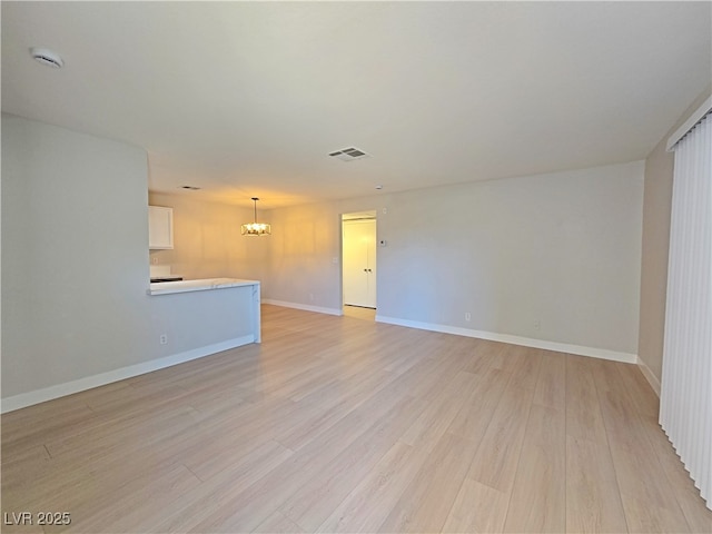 spare room with visible vents, baseboards, an inviting chandelier, and light wood finished floors