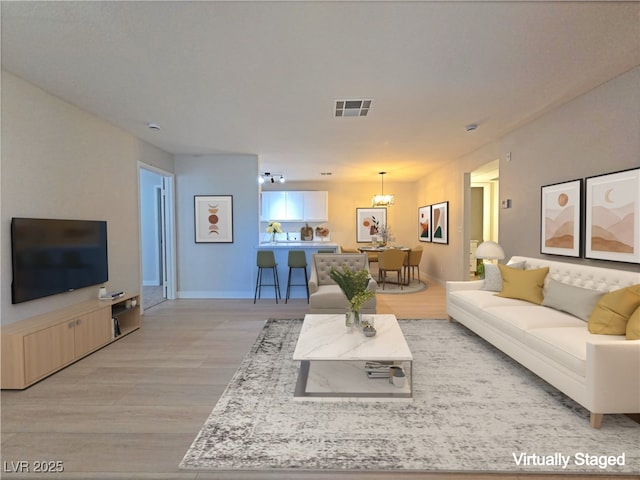 living room featuring baseboards, visible vents, and light wood finished floors