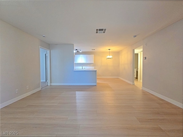 spare room featuring baseboards, visible vents, and light wood-type flooring