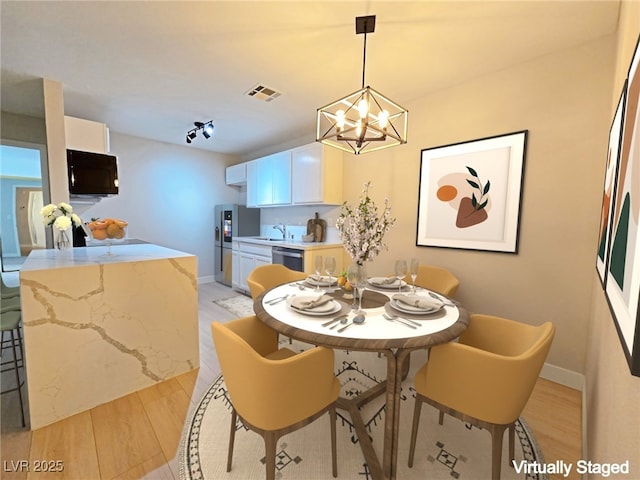 dining space with visible vents, baseboards, a chandelier, light wood-type flooring, and rail lighting