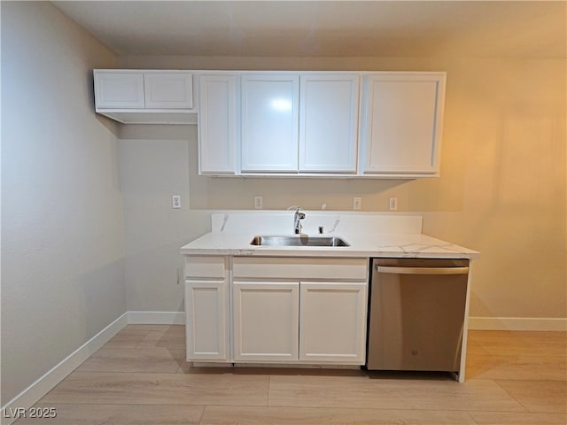 kitchen with dishwasher, white cabinets, baseboards, and a sink