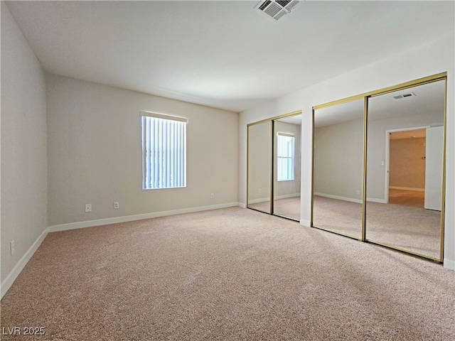 unfurnished bedroom featuring visible vents, multiple closets, baseboards, and carpet flooring