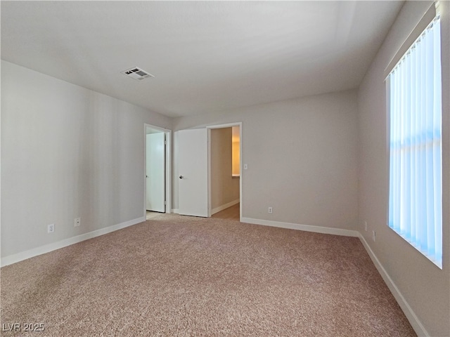 spare room featuring light carpet, visible vents, plenty of natural light, and baseboards