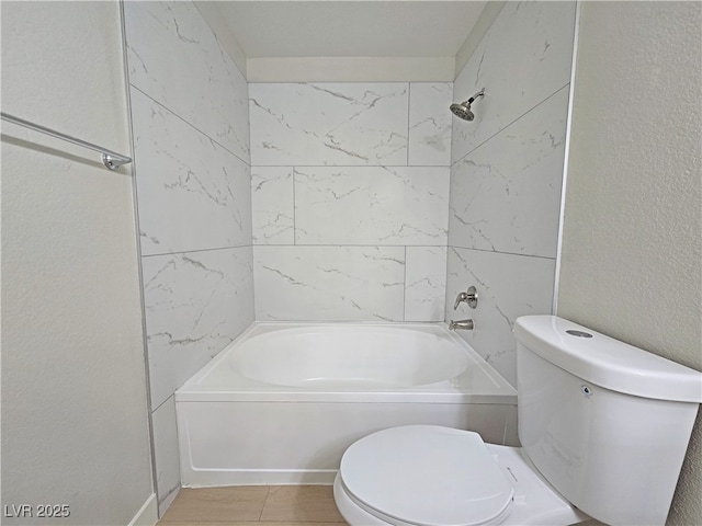 full bathroom with toilet,  shower combination, and a textured wall