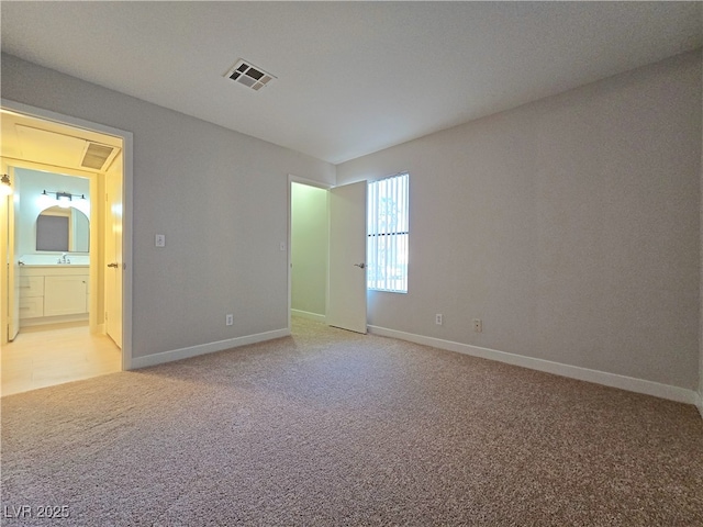 spare room featuring a sink, visible vents, light carpet, and baseboards