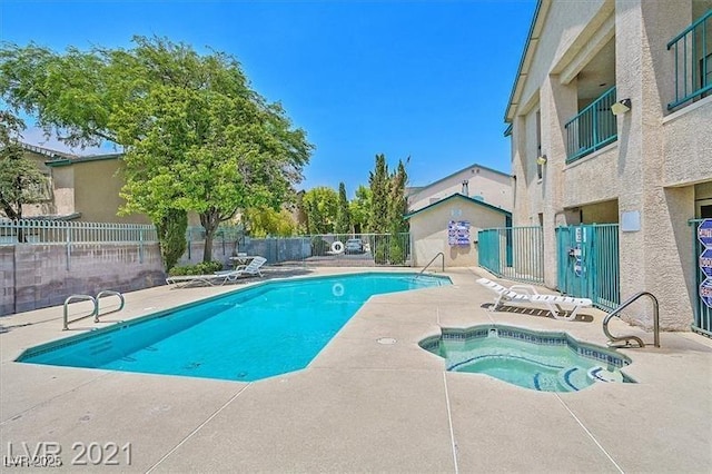 community pool featuring fence, a community hot tub, and a patio area