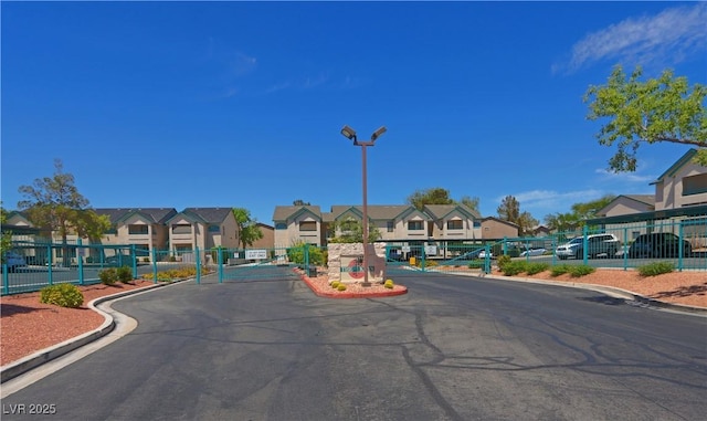 view of street with a residential view, curbs, street lights, and a gate