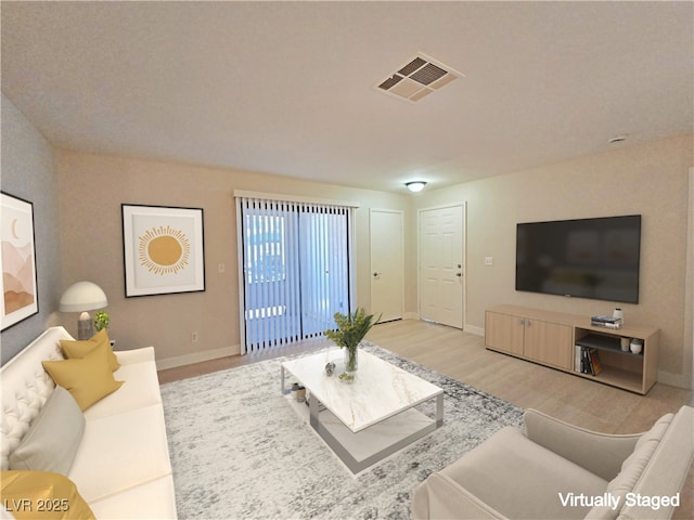 living area with visible vents, baseboards, and light wood-style flooring