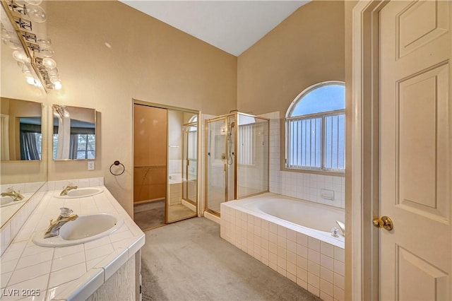 bathroom featuring double vanity, a stall shower, a garden tub, and a sink