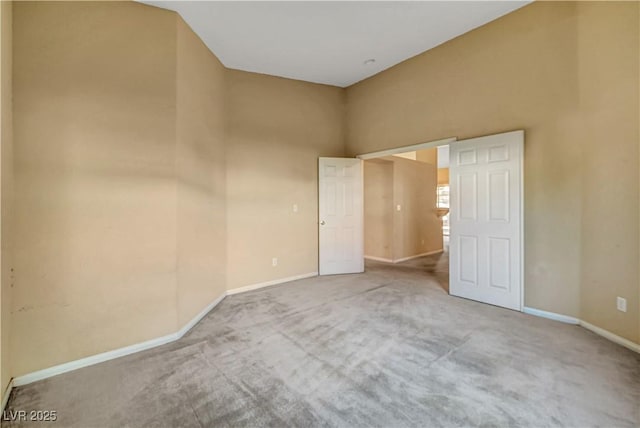 unfurnished bedroom featuring a towering ceiling, baseboards, and carpet floors