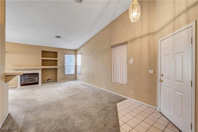 unfurnished living room with visible vents, built in shelves, baseboards, light colored carpet, and a fireplace