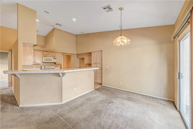 kitchen featuring visible vents, light brown cabinetry, tile countertops, a peninsula, and white microwave