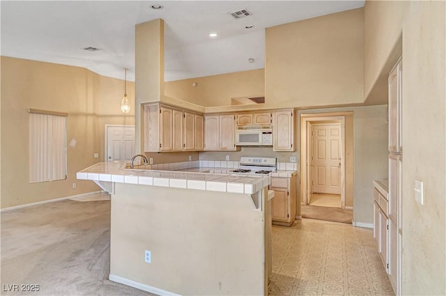 kitchen with visible vents, tile counters, a peninsula, white appliances, and high vaulted ceiling