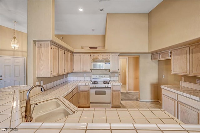 kitchen featuring white appliances, tile countertops, a high ceiling, and a sink