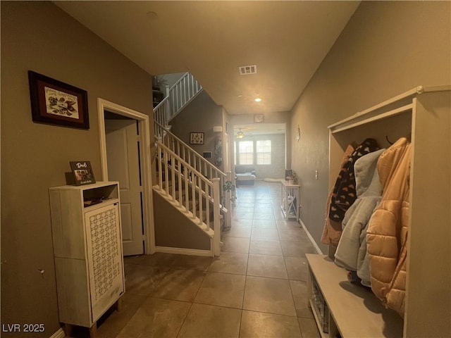 hallway with stairs, tile patterned floors, baseboards, and visible vents