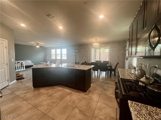 kitchen with light stone counters, visible vents, plenty of natural light, and black gas range oven