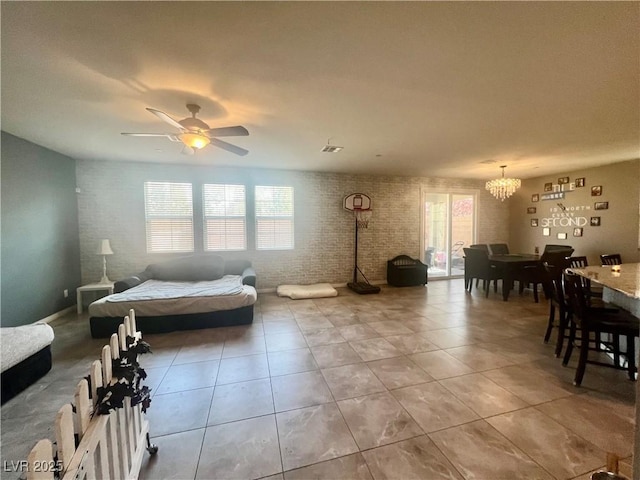 interior space with ceiling fan with notable chandelier, visible vents, and brick wall