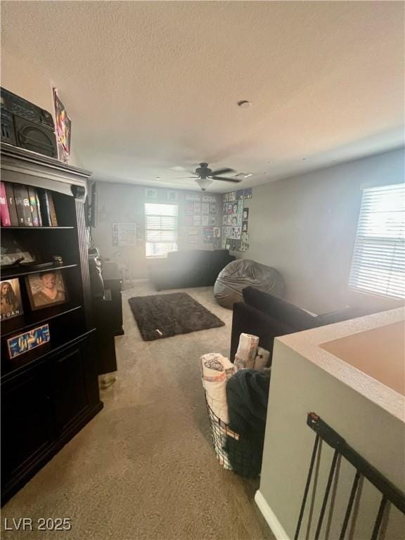 carpeted living area featuring ceiling fan and a textured ceiling