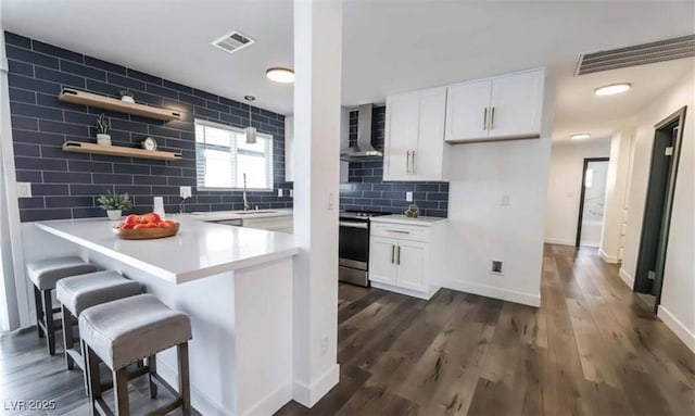 kitchen with visible vents, a peninsula, stainless steel electric range, and wall chimney exhaust hood