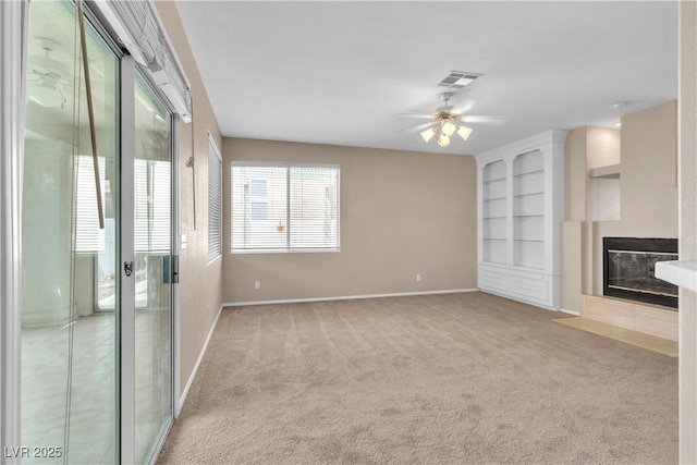 unfurnished living room featuring built in features, carpet, visible vents, baseboards, and a tiled fireplace