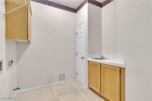 laundry room with a sink, visible vents, cabinet space, and baseboards