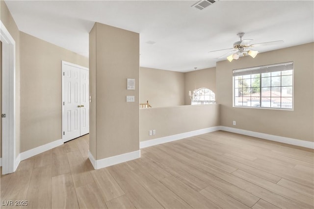 unfurnished room featuring visible vents, ceiling fan with notable chandelier, baseboards, and light wood-style floors