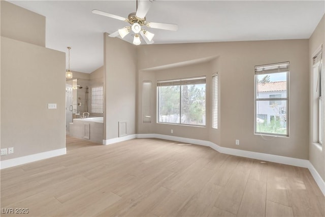 interior space with baseboards, light wood-style floors, ceiling fan, and vaulted ceiling