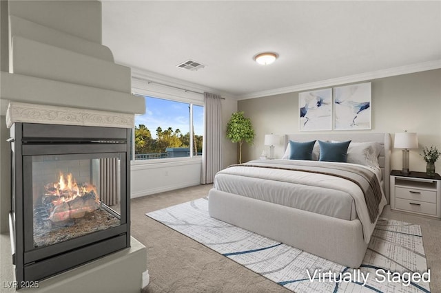 carpeted bedroom with baseboards, visible vents, a multi sided fireplace, and ornamental molding