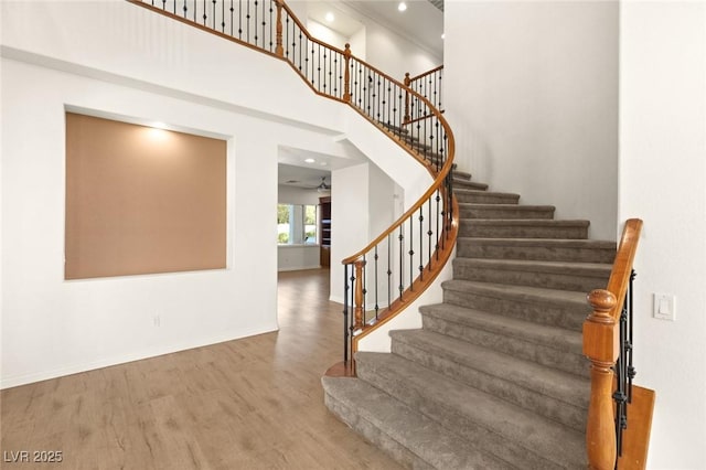 stairway featuring recessed lighting, baseboards, wood finished floors, and a towering ceiling