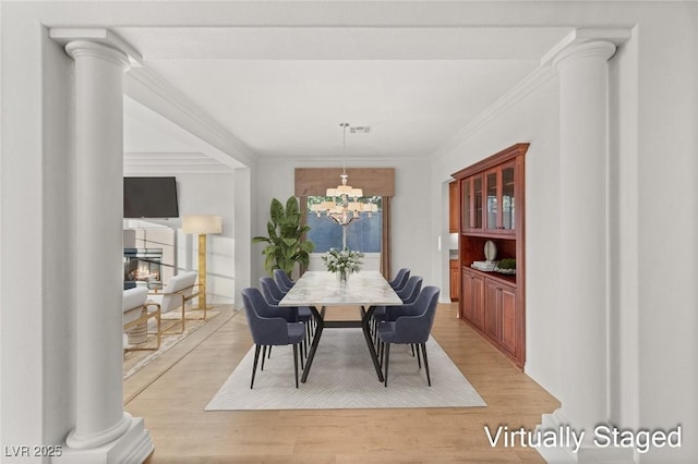 dining space with visible vents, light wood-style flooring, decorative columns, ornamental molding, and a chandelier