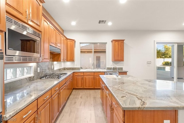 kitchen featuring a sink, visible vents, appliances with stainless steel finishes, and an island with sink