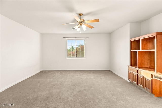 spare room with light colored carpet, baseboards, and ceiling fan