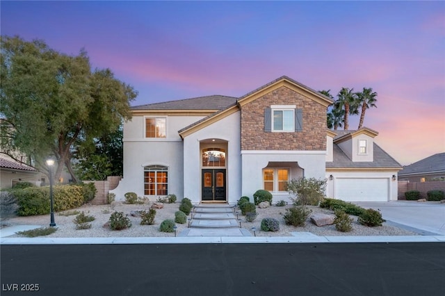 view of front of house with stucco siding, stone siding, french doors, concrete driveway, and an attached garage