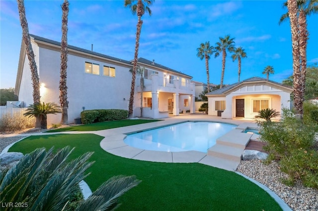 back of house with a balcony, an exterior structure, stucco siding, an outdoor structure, and a patio area