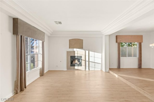 unfurnished living room featuring visible vents, light wood finished floors, ornamental molding, and a tile fireplace